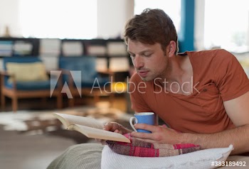 Businessman reading book and drinking tea on bed