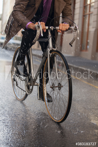 Businessman riding bicycle on rainy city street