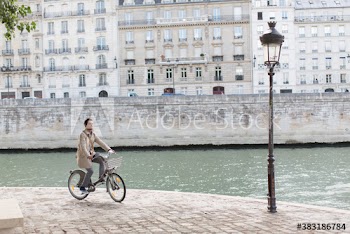 Businessman riding rented bicycle along Seine River, Paris, France