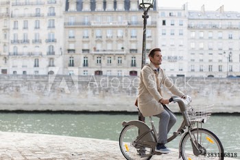 Businessman riding rented bicycle along Seine River, Paris, France