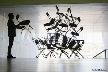Businessman stacking chairs in office