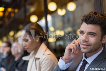 Businessman talking on mobile phone at sidewalk cafe