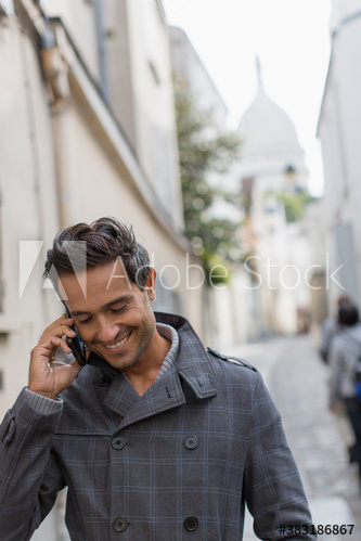 Businessman talking on smart phone on street, Montmartre, Paris