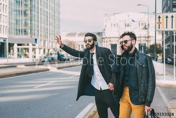 Businessman talking on smartphone while his partner asking for taxi on street