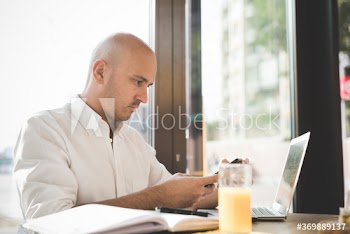 Businessman using smartphone while working on laptop