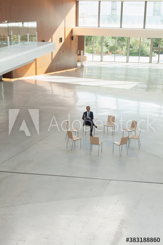 Businessman waiting in circle of chairs in modern lobby