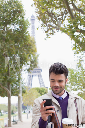 Businessman with coffee and smart phone below Eiffel Tower, Paris