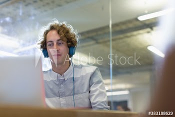 Businessman with headphones working at laptop in office