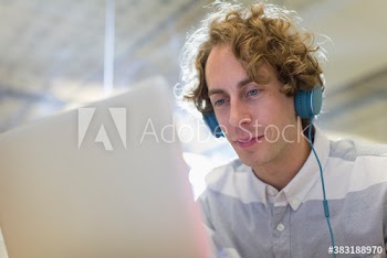 Businessman with headphones working at laptop in office
