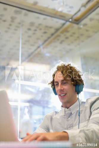 Businessman with headphones working at laptop in office