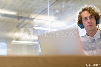 Businessman with headphones working at laptop in office