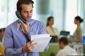 Businessman with paperwork talking on telephone in office
