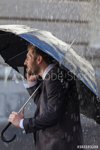 Businessman with umbrella on rainy street