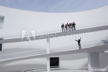 Businessman yelling up at colleagues on modern balcony in courtyard