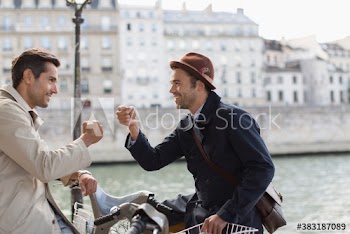 Businessmen on rented bicycles fist bumping at Seine River, Paris