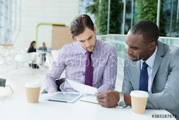 Businessmen reviewing paperwork at cafe