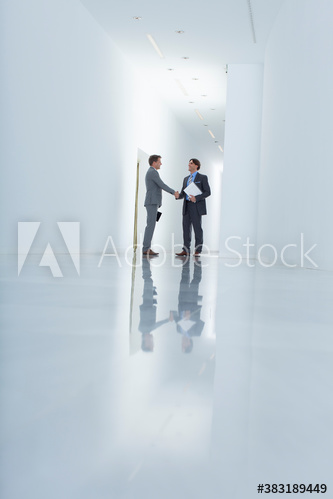 Businessmen shaking hands in modern office corridor