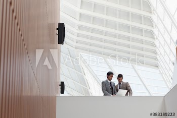 Businessmen using laptop in modern office atrium