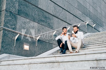 Businessmen using technology while sitting on steps