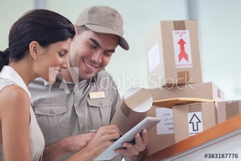 Businesswoman signing digital tablet for deliveryman with packages