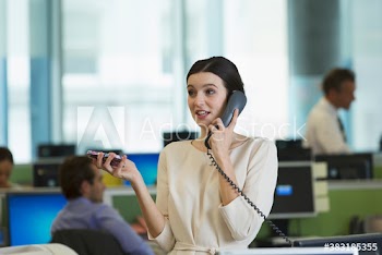 Businesswoman talking on telephone in open plan office