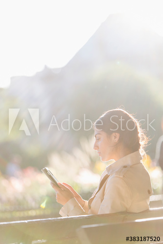 Businesswoman using digital tablet on sunny bench