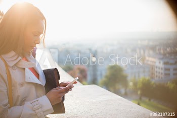 Businesswoman using smart phone on sunny balcony, Montmartre, Paris