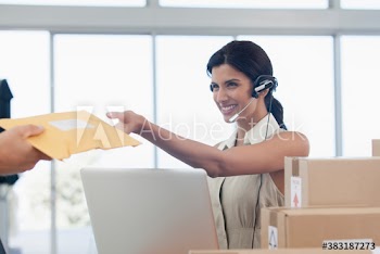 Businesswoman with headset reaching for package delivery