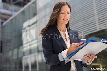 Businesswoman with paperwork using smart phone outside building
