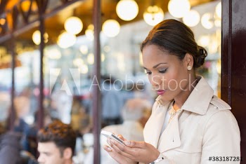 Businesswoman with smart phone at sidewalk cafe