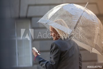 Businesswoman with umbrella using smart phone in rain