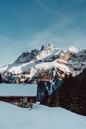 cabin and mountains covered with snow during daytime
