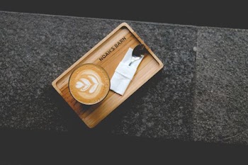 cafe latte art on glass on wooden tray
