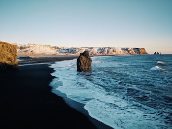 calm beach with rock formation under blue sky at daytime