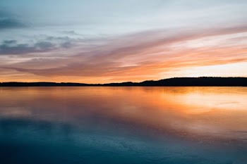 calm body of water near mountain during golden hour
