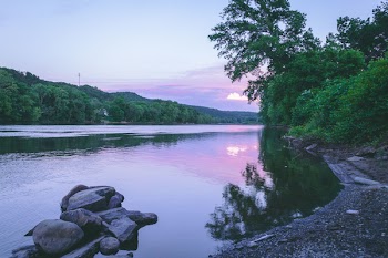 Calm Body of Water Near Rocks and Trees during Day
