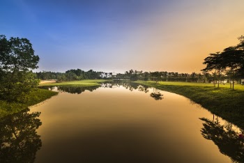 Calm Body Of Water Surrounded By Green Grass Field During Sunset