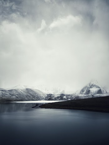 Calm Body of Water Uner White Skies