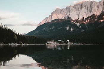 Calm Clear Lake Surface Overlooking Forest Trees and Mountain