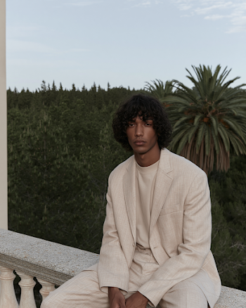 Calm Elegance: Man in Light Suit Amidst Lush Greenery
