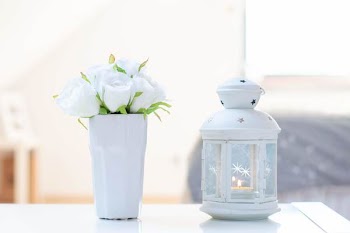 Candle Inside White Candle Lantern Beside White Flower Arrangement