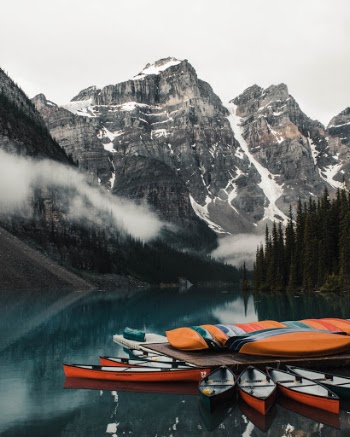 Canoes rest in the calm waters of Lake Moraine on a chilly morning.