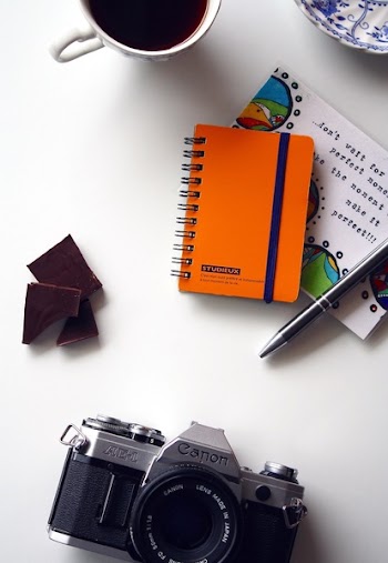 Canon Gray and Black Bridge Camera Near Orange and Blue Spiral Notebook