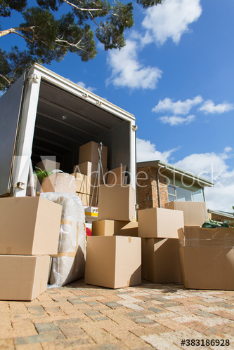 Cardboard boxes and moving van in sunny driveway outside house