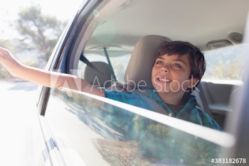Carefree boy riding in car with hand out window