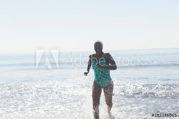 Carefree woman in bathing suit running in sunny ocean surf