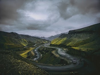 Cars Travelling on Concrete Winding Road Under Grey Cloudy Sky