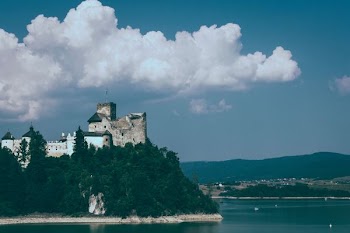 castle on cliff under white clouds and blue sky