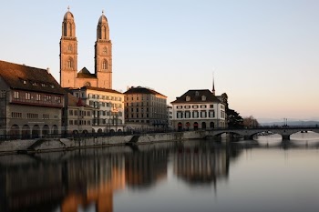 Cathedral Behind Building Beside Body of Water With Stone Bridge