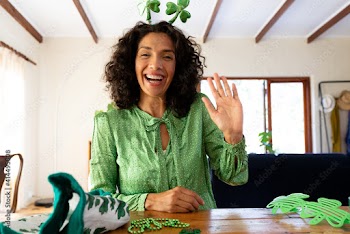 Caucasian woman dressed in green with shamrock deely boppers for st patrick's day waving during vide